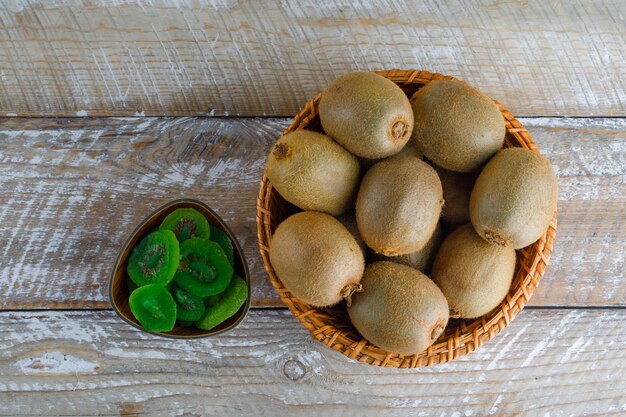 Kiwi en una canasta de mimbre con rodajas secas planas sobre una mesa de madera