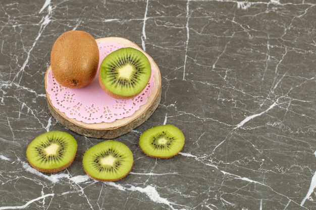 Kiwi entero y en rodajas sobre tabla de madera.