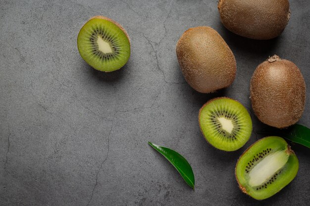 Kiwi fresco, cortado por la mitad, colocado en un piso oscuro