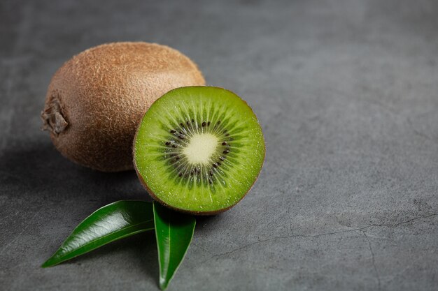 Kiwi fresco, cortado por la mitad, colocado en un piso oscuro