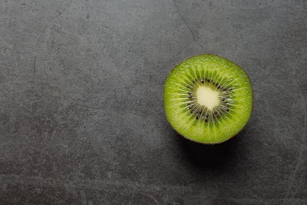 Kiwi fresco, cortado por la mitad, colocado en un piso oscuro