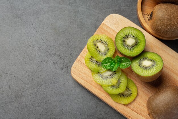 Kiwi fresco, cortado por la mitad, colocado sobre una tabla de cortar de madera