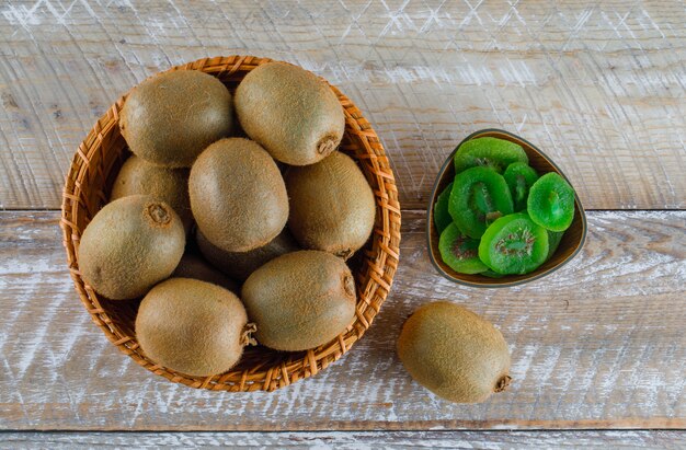 Kiwi con rodajas secas en una cesta de mimbre en la mesa de madera, plana.