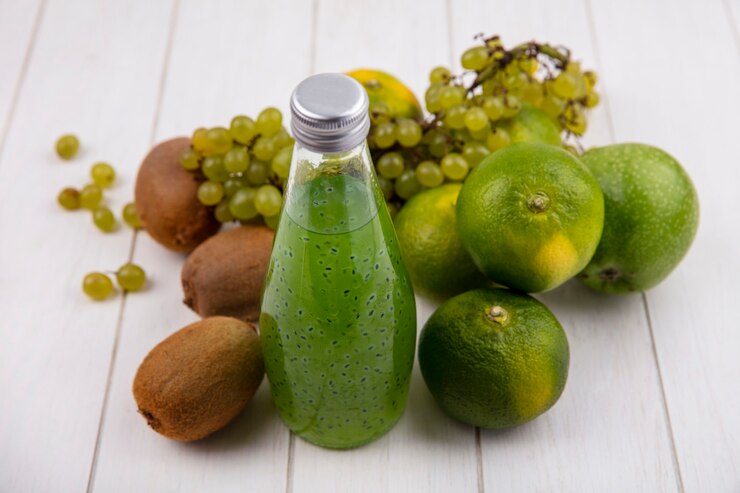 Foto gratuito kiwi de vista lateral con una botella de uvas de jugo y mandarinas en una pared blanca