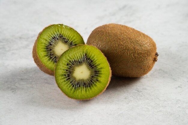 Kiwis enteros maduros y medio kiwis en blanco.