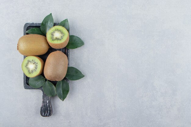 Kiwis enteros y en rodajas sobre tabla de cortar negra