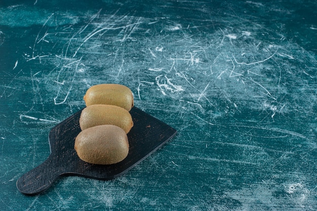 Kiwis en tabla de cortar, sobre la mesa de mármol.