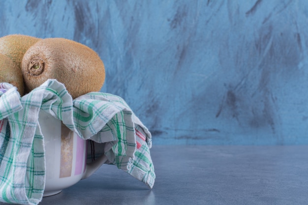 Foto gratuita los kiwis en una toalla en un recipiente sobre una mesa de mármol.