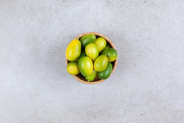 Kumquats en un cuenco de madera sobre fondo de mármol. Foto de alta calidad