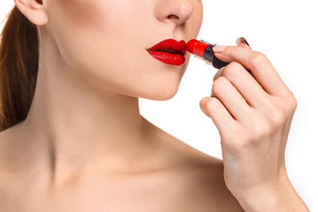 Labios femeninos hermosos con maquillaje y pomada roja sobre blanco. Proceso de trabajo del artista de maquillaje