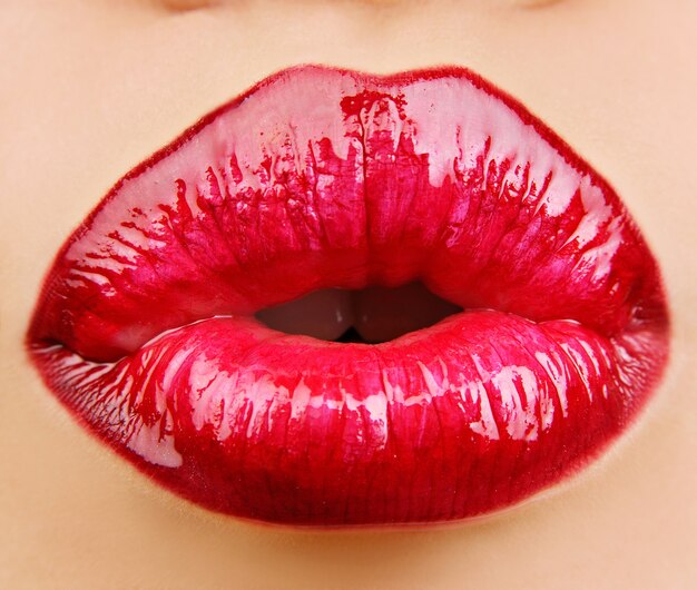 Labios de glamour rojo brillo con gesto de besos.
