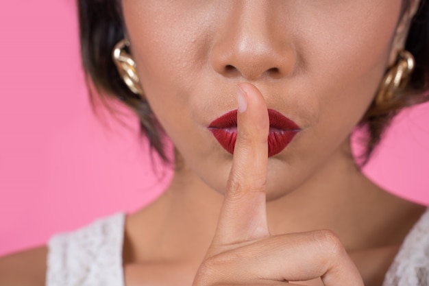 Labios rojos y dedo de la mujer asiática de la belleza que muestran la muestra del silencio del silencio