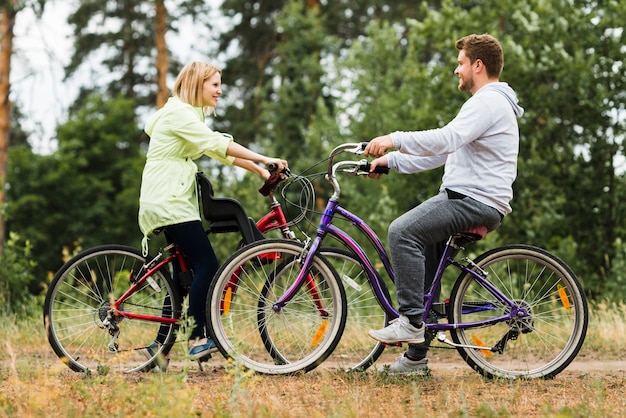 De lado feliz pareja en bicicleta