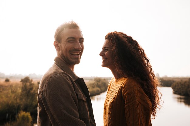 De lado feliz pareja junto a un lago