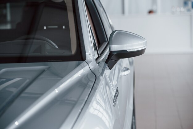 Lado izquierdo. Vista de partículas del coche blanco de lujo moderno estacionado en el interior durante el día