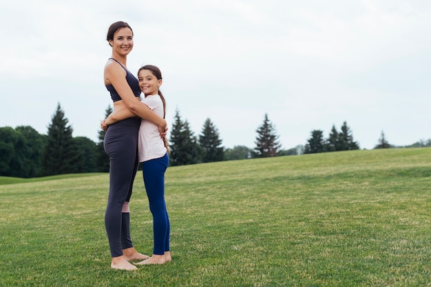 De lado madre e hija abrazándose en la naturaleza