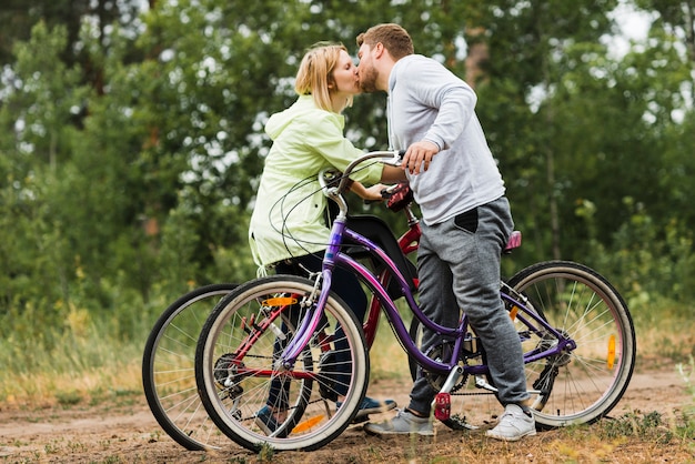 De lado la pareja se besa en bicicleta