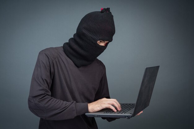 Los ladrones tienen tarjetas de crédito usando una computadora portátil para actividades de piratería de contraseñas.