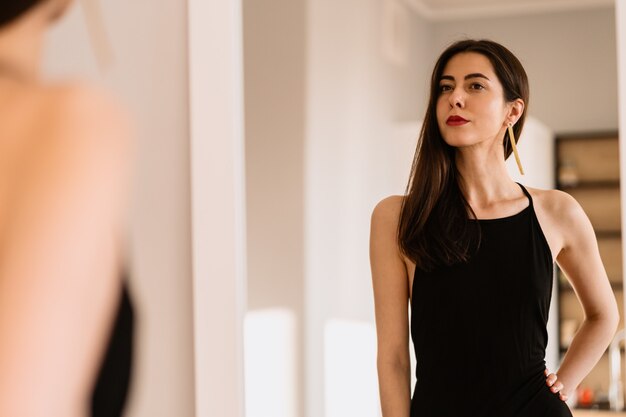 Lady lleva un hermoso vestido negro mirándose al espejo