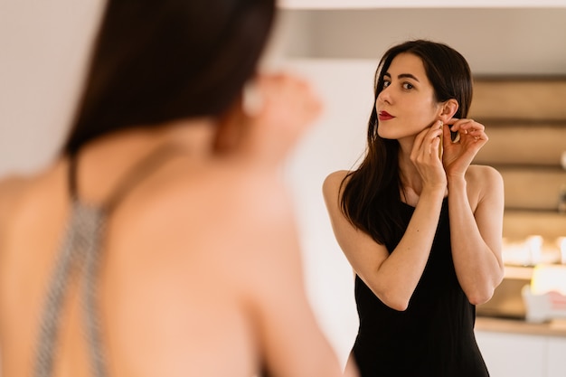 Lady lleva un hermoso vestido negro mirándose al espejo