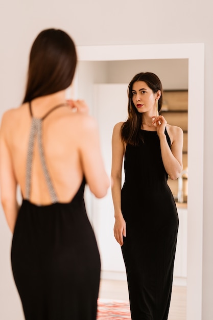 Lady lleva un hermoso vestido negro mirándose al espejo