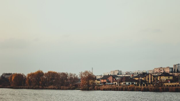 Lago claro rodeado de árboles y casas en otoño