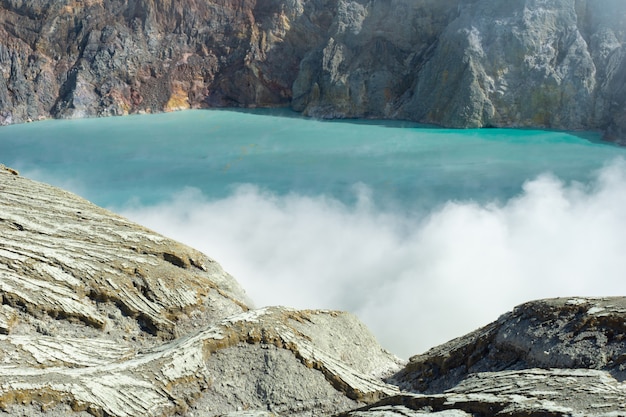 Lago expulsando humo rodeado de rocas