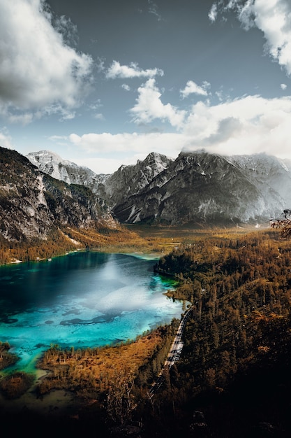 Lago en medio de montañas bajo nubes blancas y cielo azul durante el día