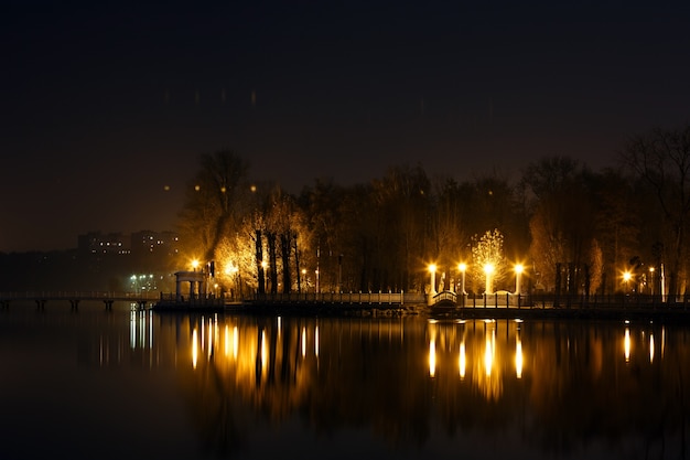 Lago por la noche con una casa y luces