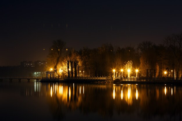 Lago por la noche con una casa y luces