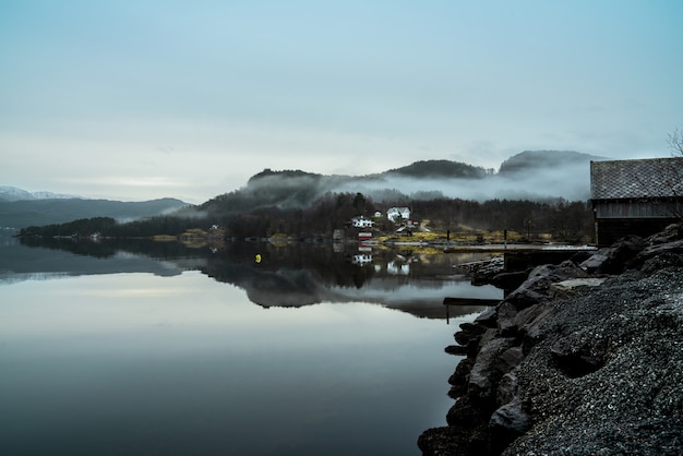 Lago rodeado de colinas cubiertas de niebla con el verdor que se refleja en el agua