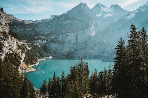 Lago rodeado de rocas cubiertas de nieve y bosques bajo la luz del sol