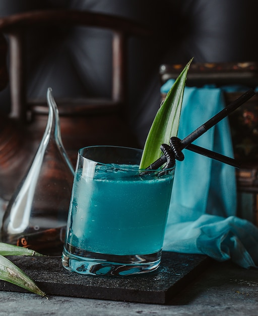 Laguna azul en un vaso con hojas de piña y pajitas negras