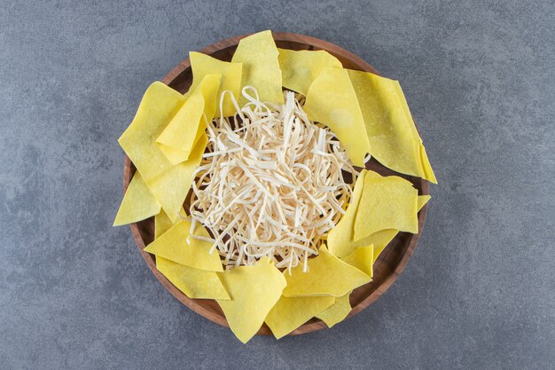 Láminas de queso Cecil y lasaña sobre un plato de madera, sobre la superficie de mármol.