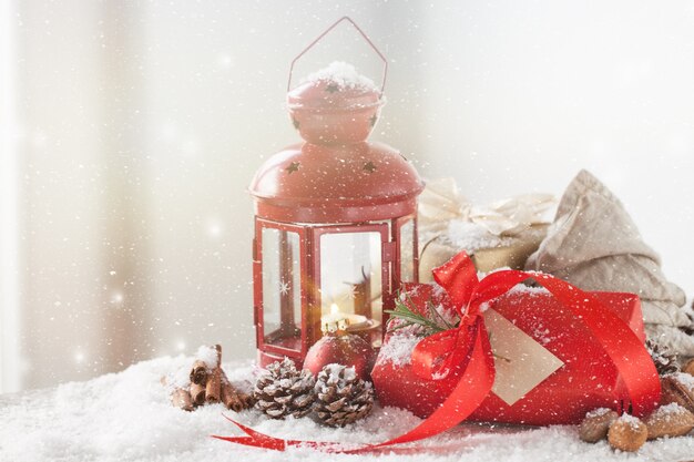 Lámpara antigua con un regalo rojo mientras nieva