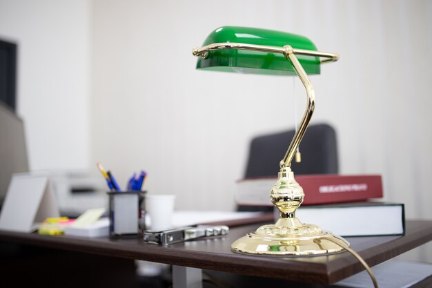 Lámpara de escritorio verde en una oficina con libros y archivos