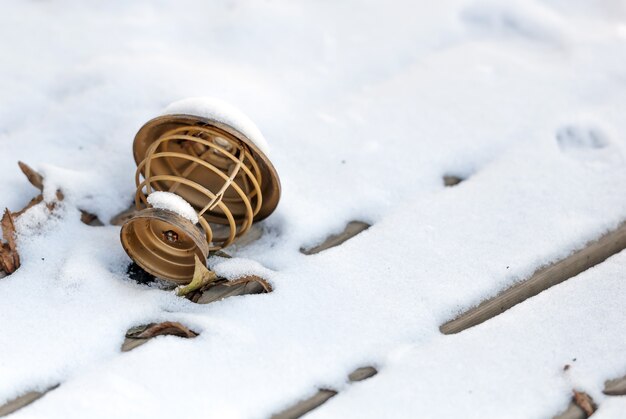 Lámpara marrón de madera arrojada sobre la nieve junto a una hoja en invierno