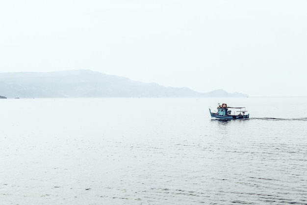 Lancha en el mar rodeada de montañas envueltas en niebla