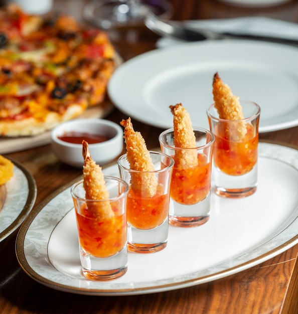 Foto gratuita langostinos fritos crujientes servidos en vasos de chupito con salsa de chile dulce