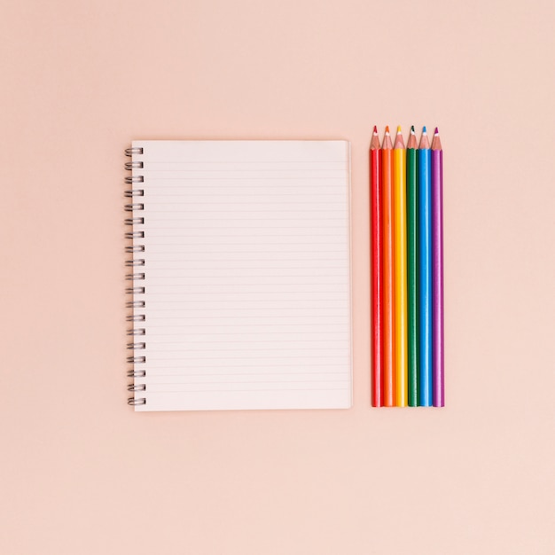 Lápices de colores del arco iris y cuaderno.