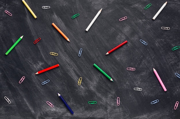 Foto gratuita lápices de colores y clips de papel en la pizarra