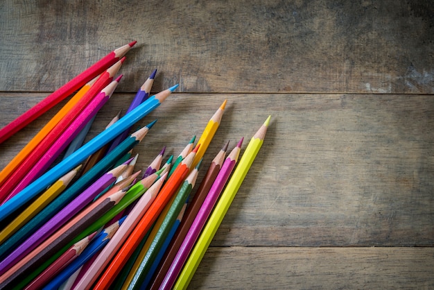 Lápices de colores y cuaderno sobre un fondo de madera