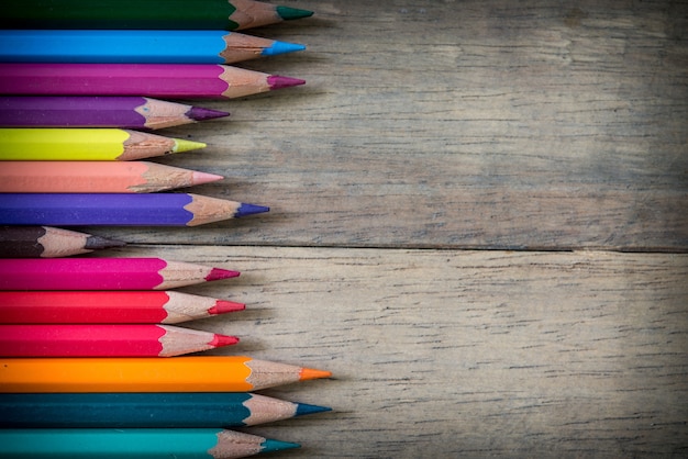 Lápices de colores y cuaderno sobre un fondo de madera