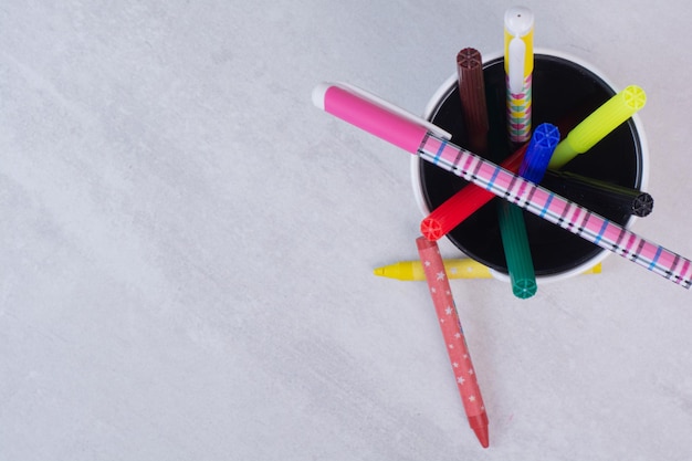 Lápices de colores en estuche sobre mesa blanca.