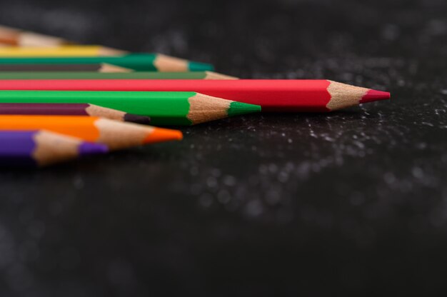 Lápices de colores con forma de triángulo en superficie negra con espacio de copia.