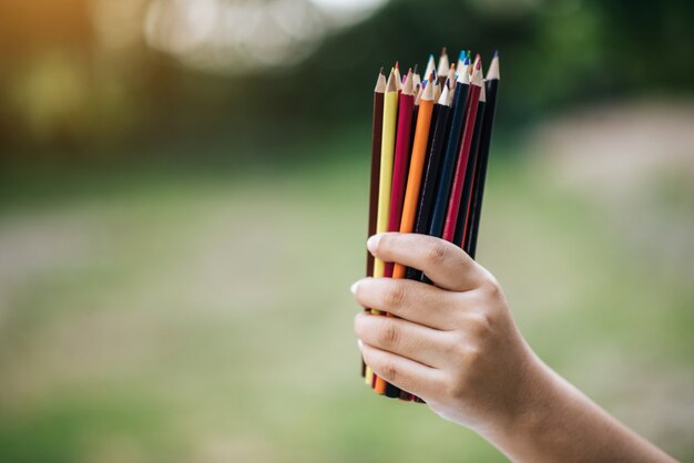 Lápices de colores en mano sobre fondo verde