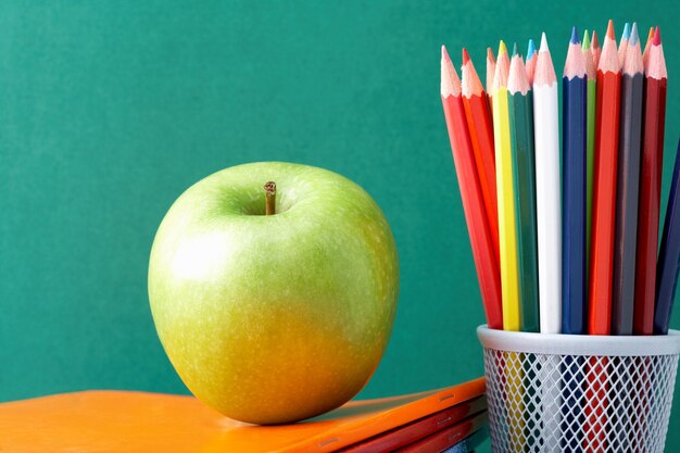 Lápices de colores con una manzana verde