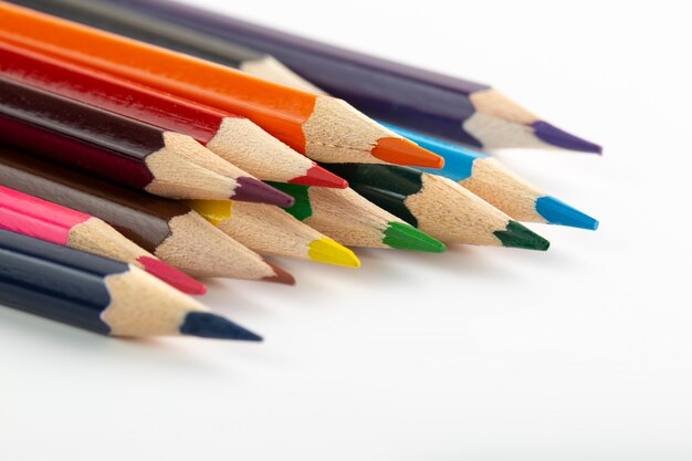 Lápices de colores multicolores para dibujar alineados en la pared blanca