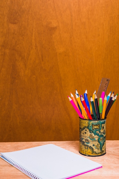 Lápices y cuaderno sobre fondo de madera