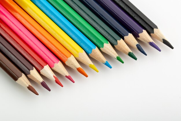Lápices de dibujo multicolores alineados brillantes en el escritorio blanco